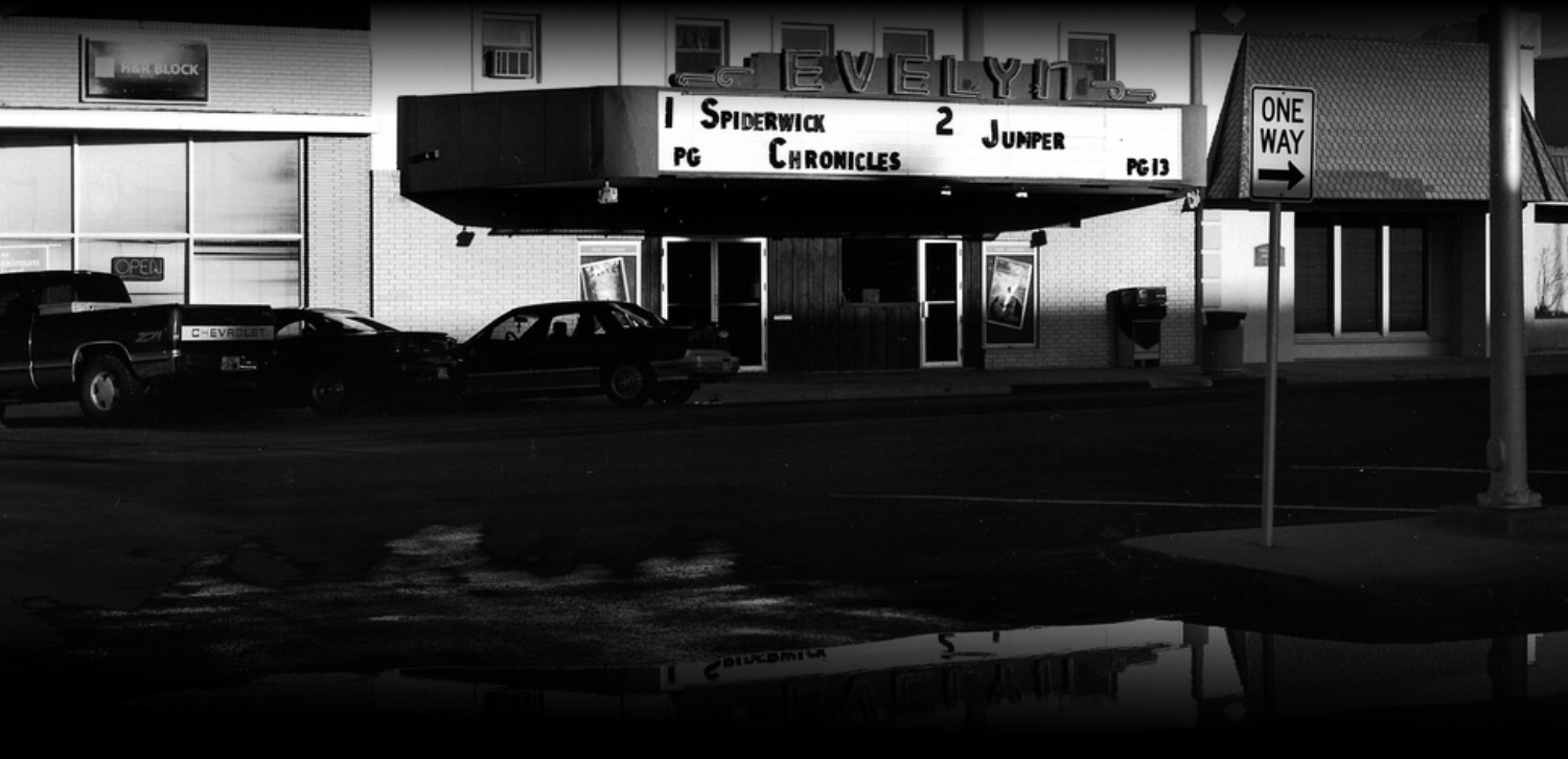 The front of the Evelyn on Bliss Avenue at night, with the marquee lit above the entrance.